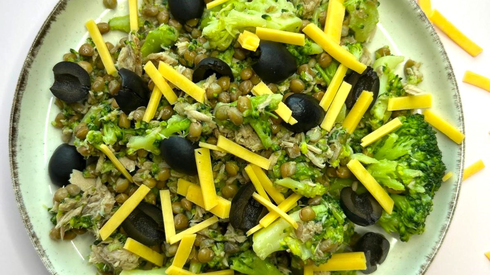 broccoli salade bord glutenvrije broccolisalade op een roze achtergrond met snippers cheddar cheese