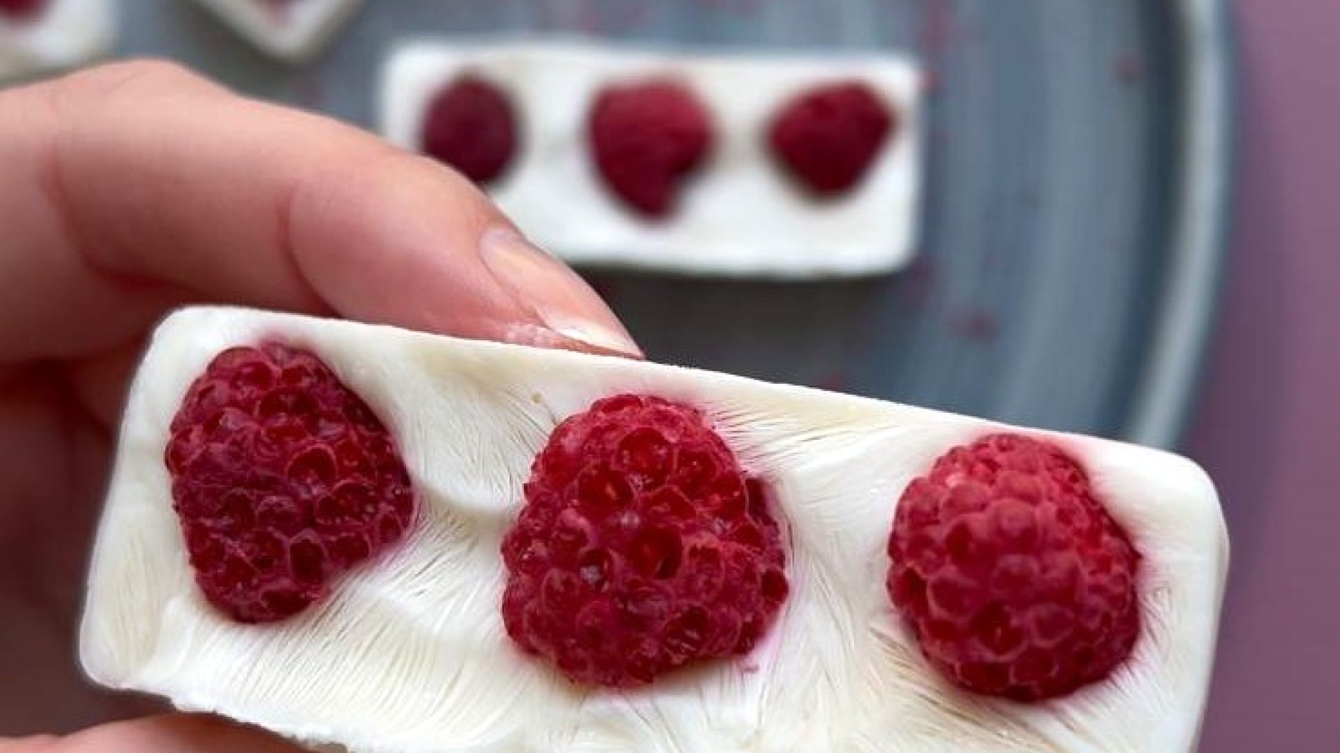 glutenvrije yoghurt ice bark in hand en op de achtergrond nog meer op een blauw bord.